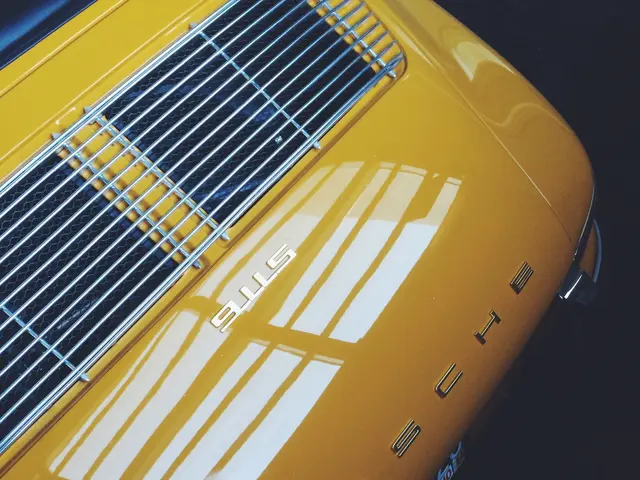 The image shows a close up of a yellow Porsche 911 parked in a parking lot. The car is a bright...