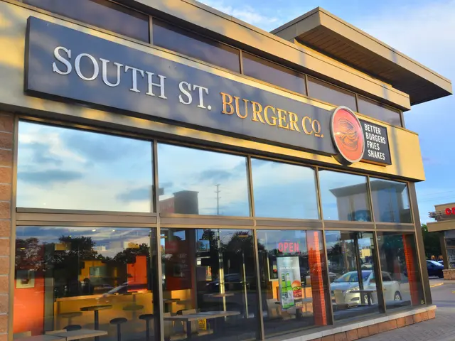 The image shows a South St Burger Co. restaurant with glass walls and doors, a name board on the...