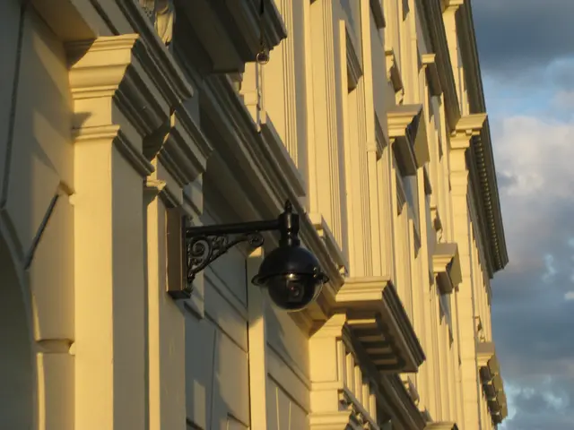 The image shows a building with a security camera mounted on the side of it, illuminated by a light...
