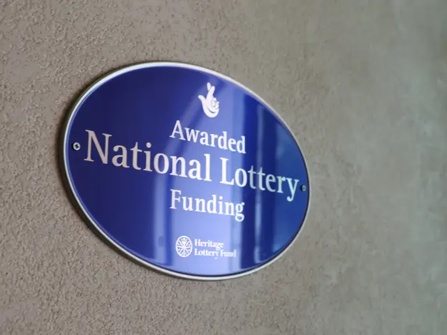 The image shows a blue plaque on the side of a building that reads "Awarded National Lottery...