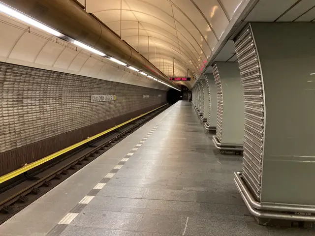 The image shows a subway station with a train on the tracks, illuminated by lights attached to the...