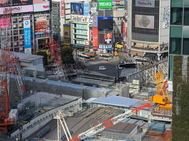 The image shows a bustling city street in Tokyo, Japan, with tall buildings, vehicles on the road,...