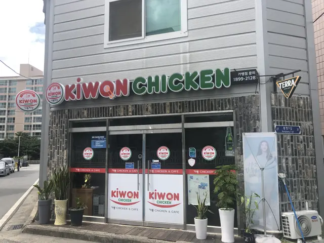 The image shows a Kiwon Chicken restaurant in Seoul, South Korea. It is a building with glass doors...