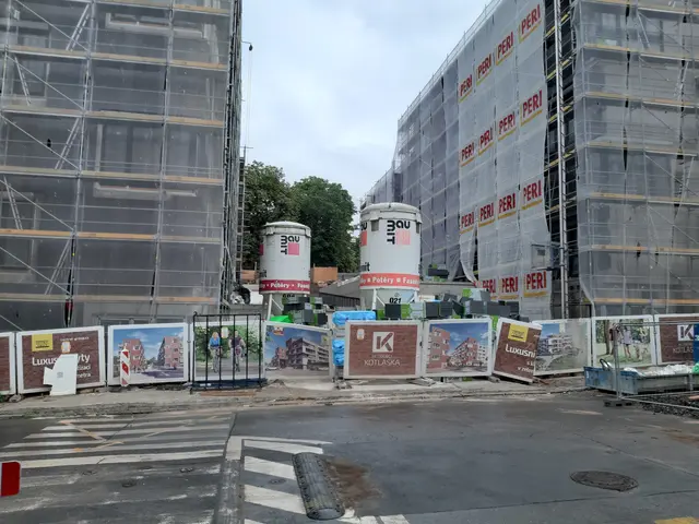 The image shows a construction site with a large building under construction in the background,...