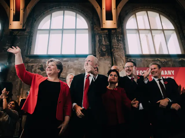 The image shows a group of people standing next to each other in front of a crowd, clapping their...