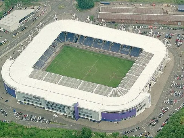The image shows an aerial view of a soccer stadium in the middle of a city, surrounded by...