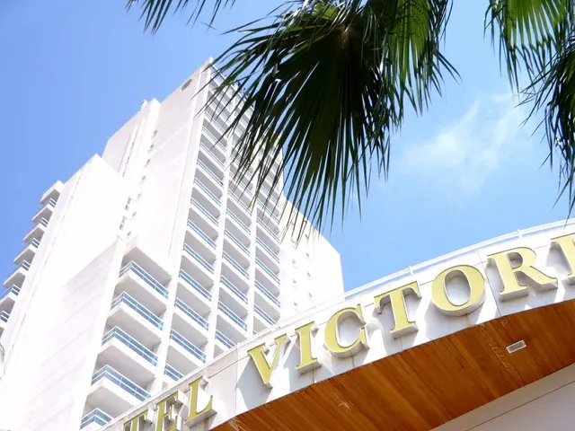 The image shows the Hotel Victoria in Miami Beach, Florida. It is a tall building with glass...