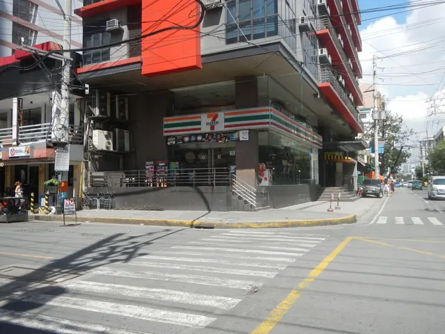 The image shows a bustling city street with vehicles driving on the road, people walking on the...