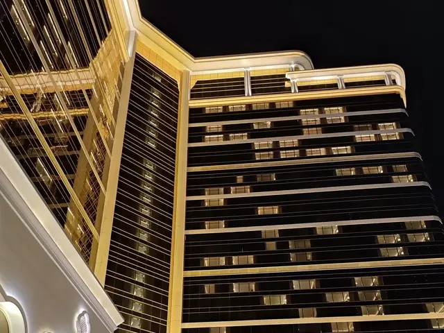 The image shows the Wynn Hotel and Casino in Las Vegas, Nevada. It is a large building with glass...