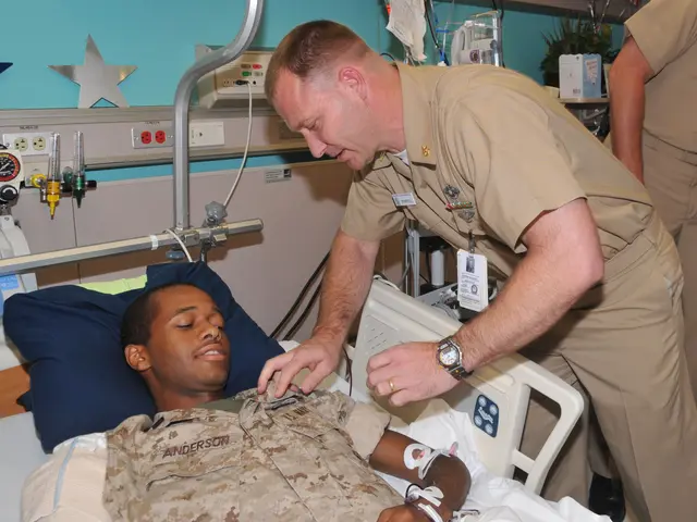 The image shows a man in a military uniform lying on a hospital bed with a pillow beneath his head....