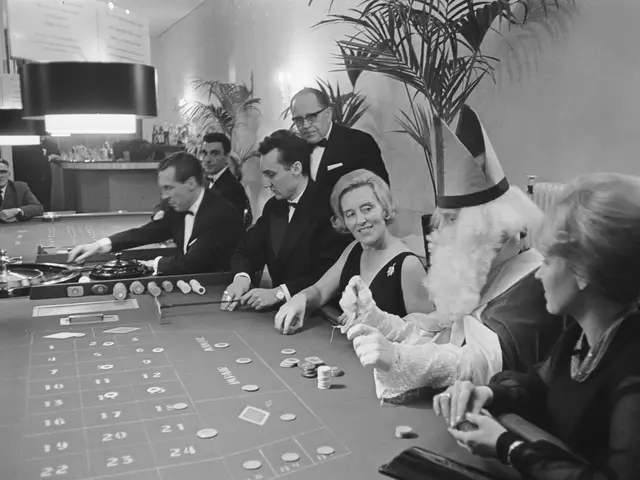 The image shows a group of people sitting around a roulette table in a casino. The table is black...