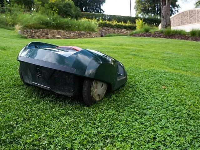 The image shows a robotic lawn mower sitting atop a lush green field, surrounded by plants, trees,...