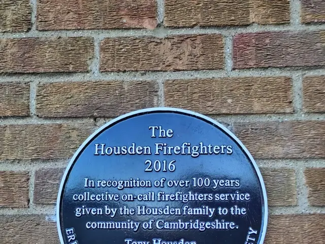 The image shows a plaque on the side of a brick building that reads "Housden Firefighters 2016"....