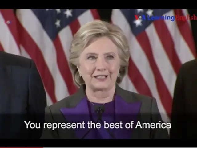 The image shows Hillary Clinton speaking at a podium in front of an American flag, with two men...