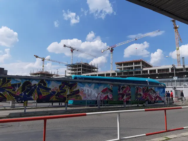 The image shows a train with graffiti on the side of it parked in front of a building under...