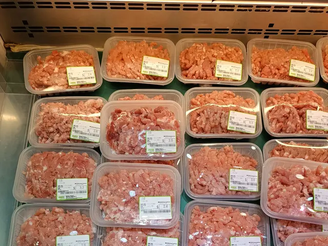 The image shows a display case filled with lots of different types of meat in plastic containers,...