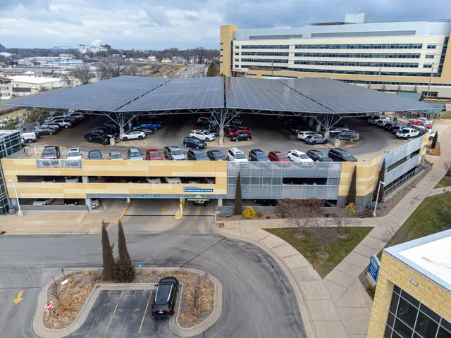 The image shows an aerial view of a parking lot with cars parked in it, surrounded by buildings,...