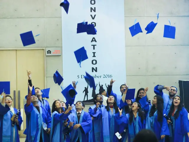The image shows a group of people in blue graduation robes and hats throwing their hats in the air...