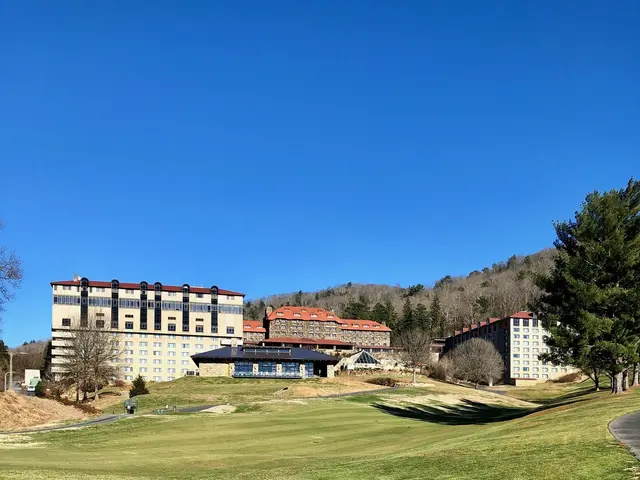 The image shows a golf course with a large building in the background, surrounded by lush green...