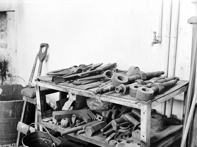 The image shows a black and white photo of a workbench with a variety of tools on it. On the left...