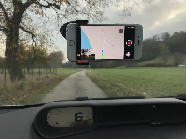 The image shows a car dashboard with a cell phone attached to it, a speedometer, a windshield...