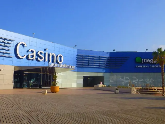 The image shows a casino building with palm trees in front of it, surrounded by plants in pots, a...