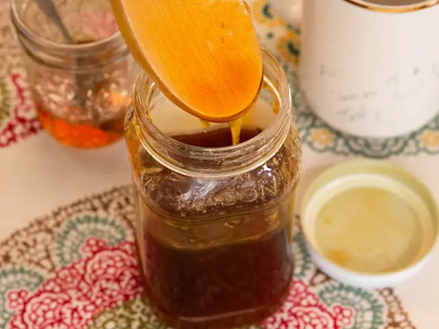 The image shows a table with a cloth on it, a jar of honey with a wooden spoon in it, two other...
