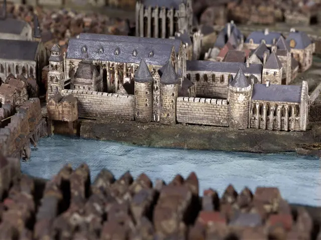 The image shows a model of a city with a river running through it, featuring a few buildings and a...