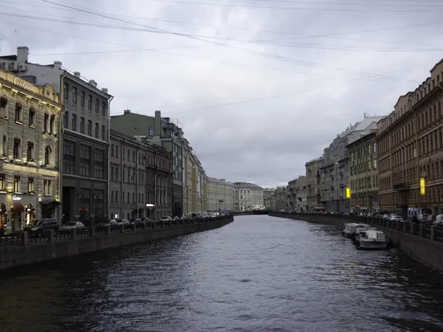 The image shows a canal in St. Petersburg, Russia, with boats on the water, a railing along the...