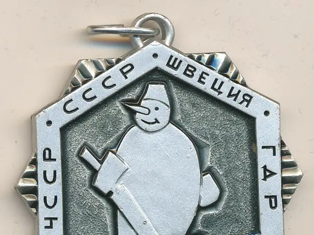 The image shows a silver medal with a snowman on it. The medal is in the shape of a locket and has...